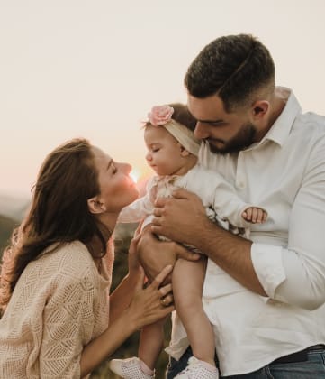 a mother and father holding their baby up in the air