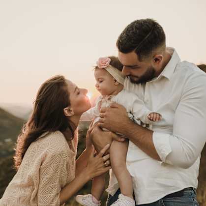 a mother and father holding their baby up in the air