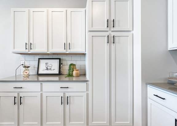 A kitchen with white cabinets and a framed picture on the counter.