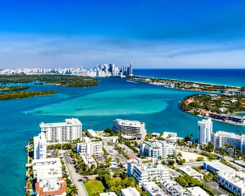 A cityscape with a body of water in the foreground and a clear blue sky above.