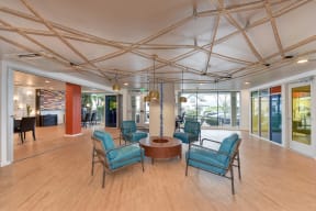  Leasing Office with Hardwood Inspired Floor, Blue Sofa Chairs, Hanging Ceiling Lights and Exit Door