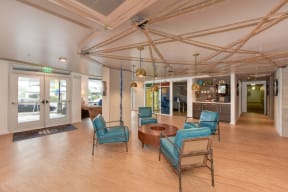  Leasing Office with Hardwood Inspired Floor, Blue Sofa Chairs, Hanging Ceiling Lights and Exit Door