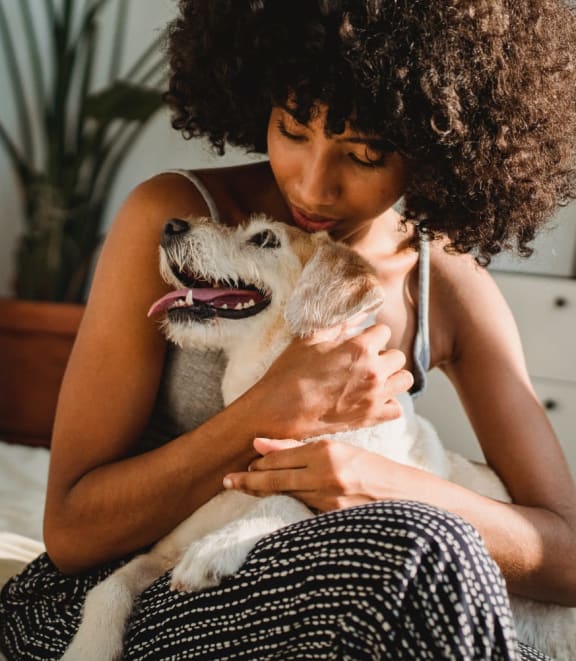 a woman sitting on a bed with her dog