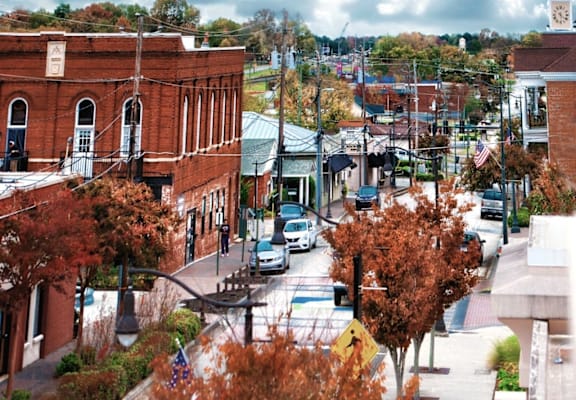 A street view of a town with a clock tower in the background.