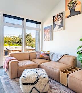 a living room with a brown couch and a large window at Society 62 Apartments, Portland 97213