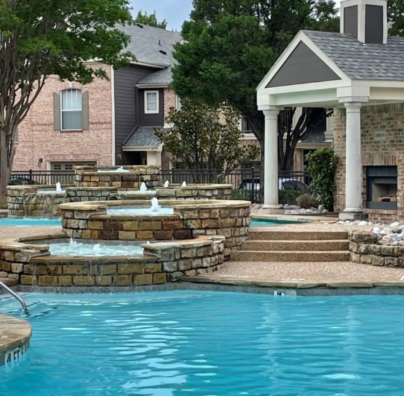 a pool with a gazebo and waterfalls in front of a house