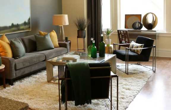 A living room with a grey couch, a white coffee table, and a black chair.