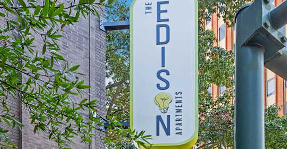 A sign for The Edison Apartments hangs from a pole.
