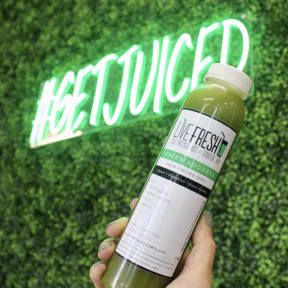 a hand holding a bottle of green juice