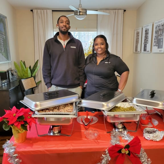 a man and a woman standing in front of a table full of food