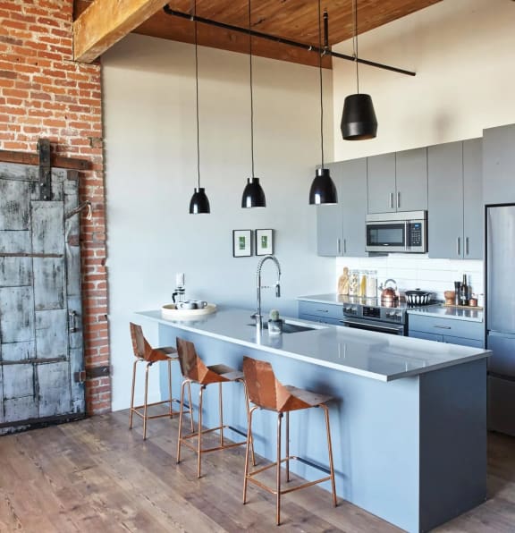 a kitchen with a large island with three stools in front of it at The Platform in Norwalk, CT