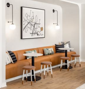 a living room with a orange couch and stools and a painting on the wall