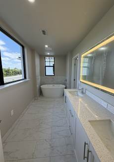 A bathroom with a tub, sink, and large windows.