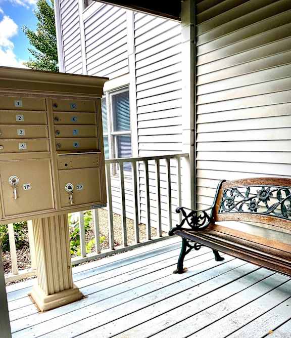 A bench sits on a porch next to a mailbox.