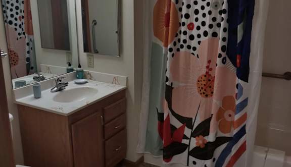 A bathroom with a toilet, sink, mirror, and shower curtain.