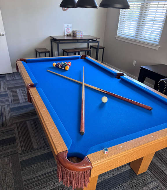 A group of people playing pool in a bright room.