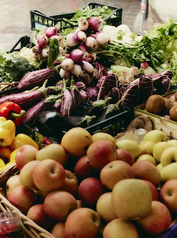 A variety of fruits and vegetables are displayed in baskets and crates.