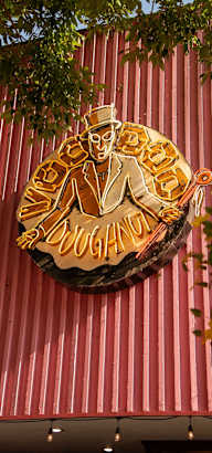A sign with a man holding a guitar is hanging from a red building.