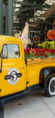 an old yellow truck with flowers in the bed of it