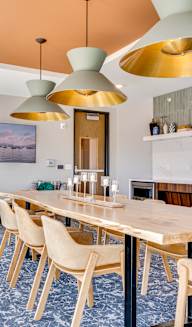 a long wooden table with chairs in a room with a fireplace and a painting on the wall