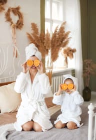 a woman and a child sitting on a bed with oranges as sunglasses at Sterling Creek, Richmond Hill