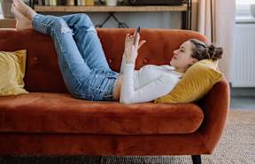 a woman laying on a couch using her cell phoneat The Robert Apartments, Madison, AL 35758