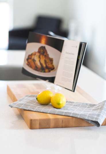 a cutting board with lemons and a book on a table
