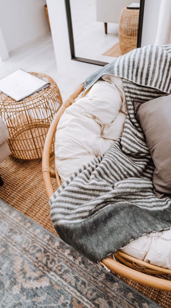 a woven chair with a blanket on top of it in a living room