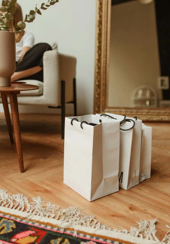 three white shopping bags sitting on the floor in front of a mirror