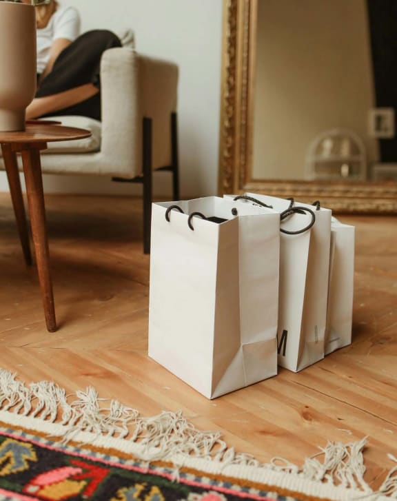 three white shopping bags sitting on the floor in front of a mirror