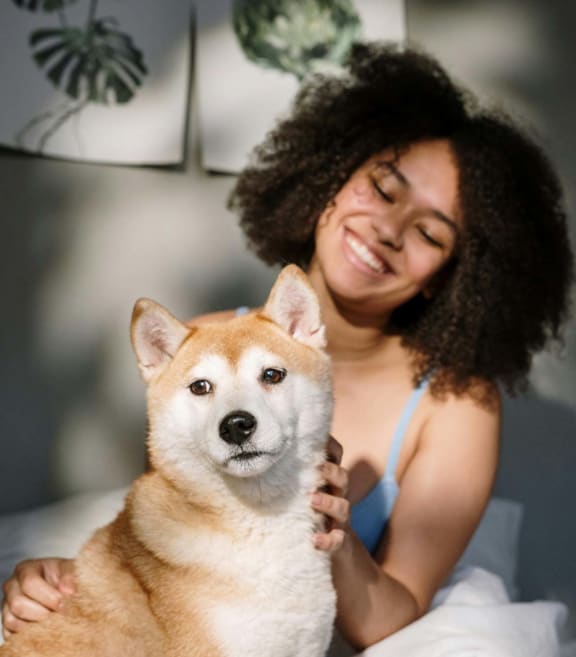 a woman sitting on a bed with a dog