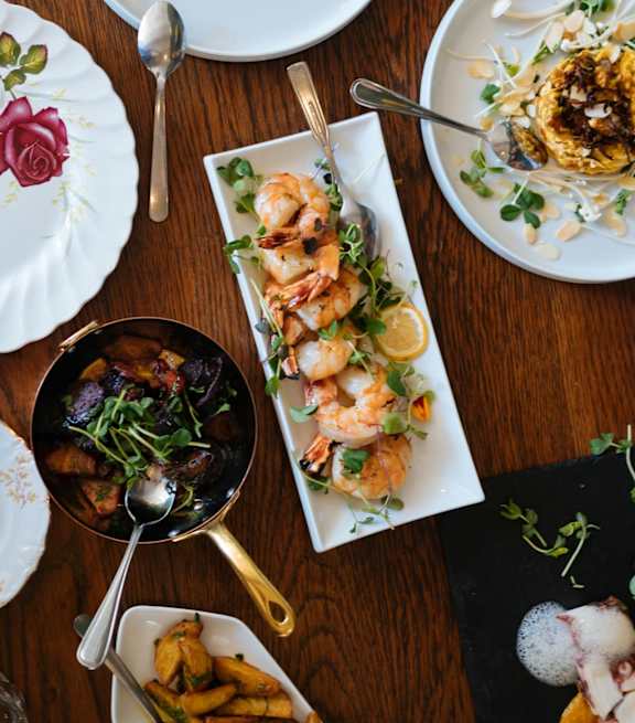 A wooden table with plates of food and silverware.