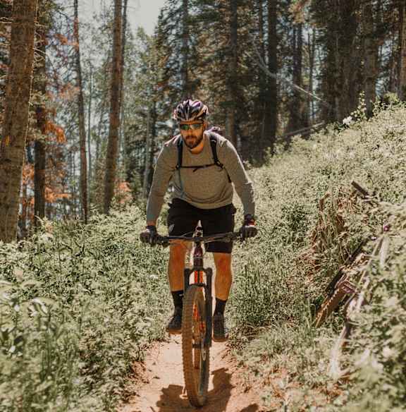 A man riding a bicycle on a dirt trail in the woods.