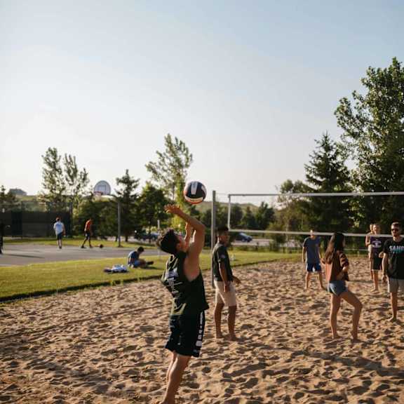 A group of people playing volleyball on a sandy beach.