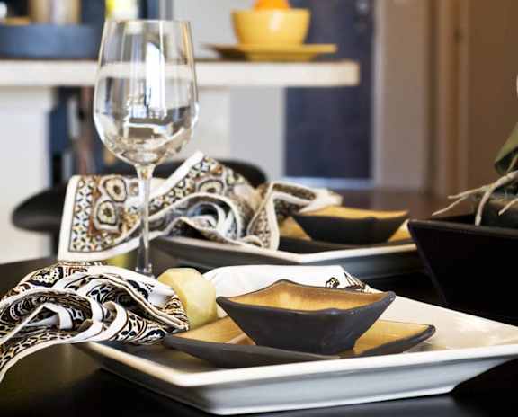 A table set for a meal with a wine glass and a bowl of fruit.