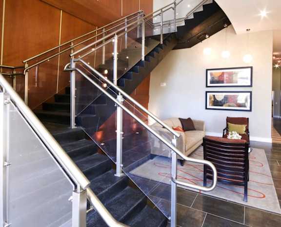 A staircase with a metal railing and a couch in the background.
