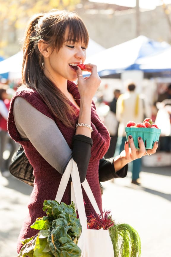 Woman at the market eating a strowberry