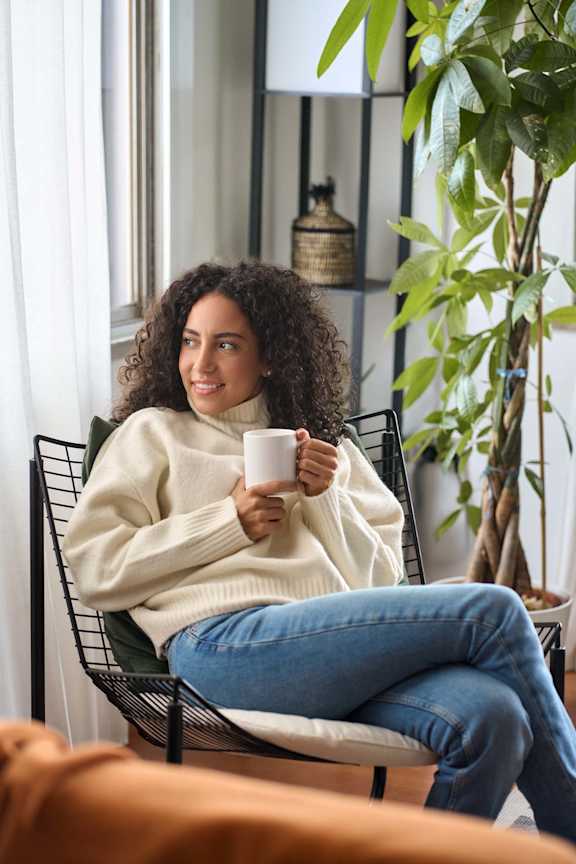 a woman sitting in a chair holding a cup of coffee