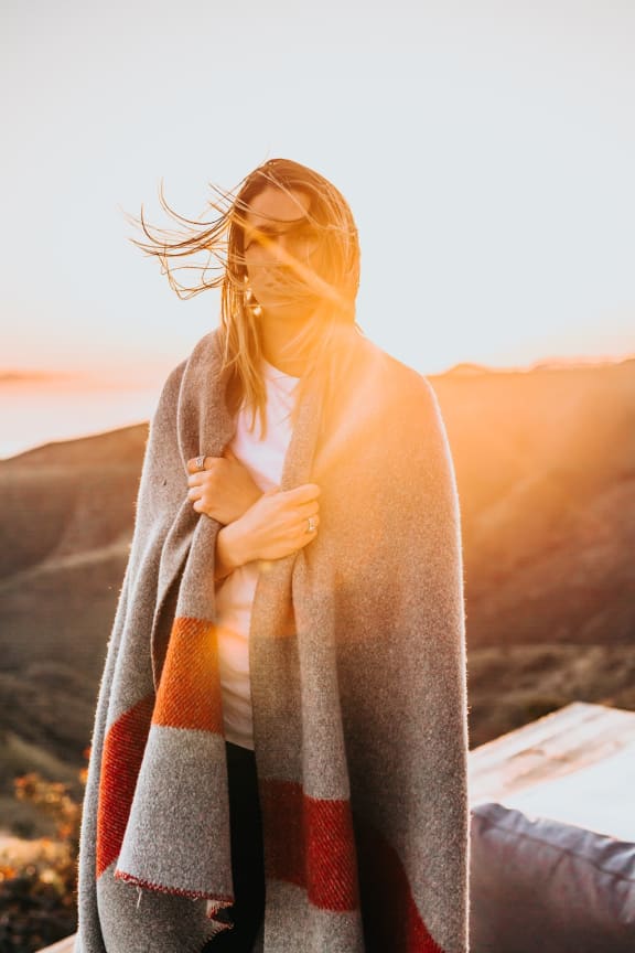 Woman Holding Blanket in Front of Sunset
