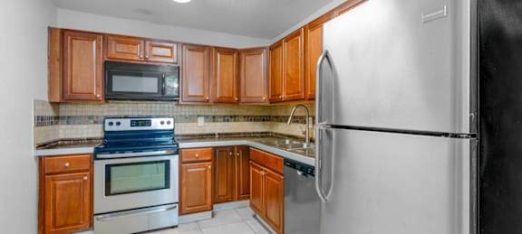 A kitchen with a black refrigerator and wooden cabinets.