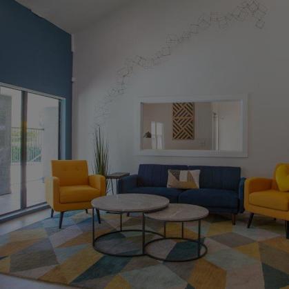 A living room with a blue couch, yellow chairs, and a coffee table.