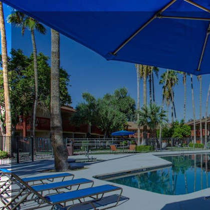 A pool area with sun loungers and a blue umbrella.