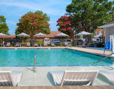 A pool with two lounge chairs in the foreground.