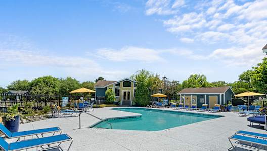 a swimming pool with lounge chairs and umbrellas next to a resort style pool