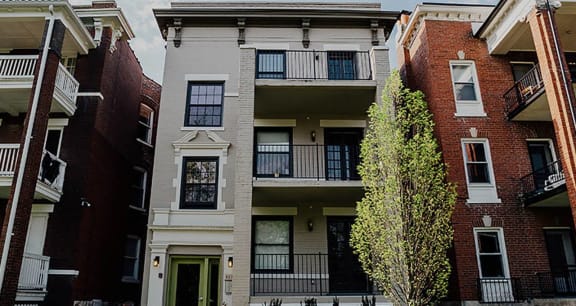 a two story apartment building with a tree in front of it