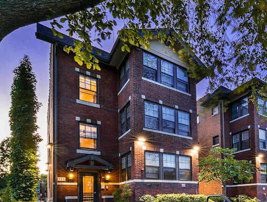 the exterior of a condo building at night with lights on