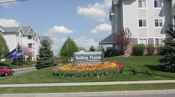 A flower bed in front of a sign for Rolling Prairie Apartments.