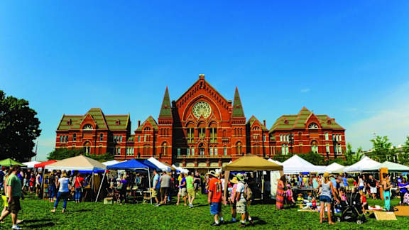 A large red building with a clock tower is surrounded by tents and people.at Sky Central, Cincinnati, 45202