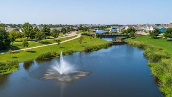 A fountain in the middle of a pond in a park.