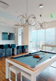 Clubhouse with pool table, bar, flatscreen televisions, and floor to ceiling windows showing views of Philadelphia